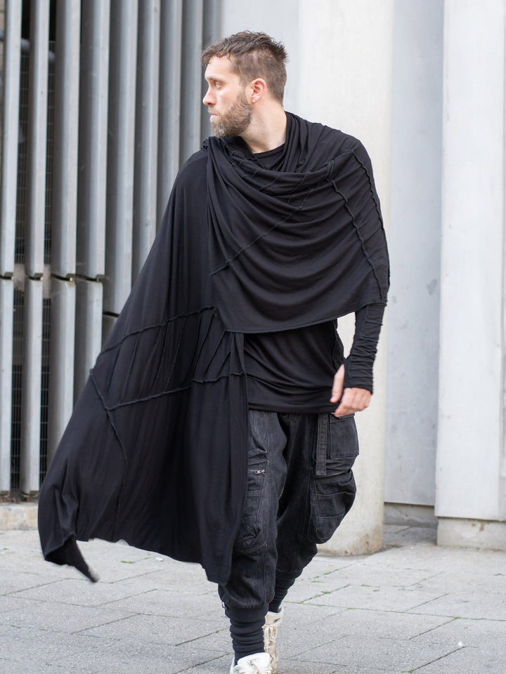 Black oversized avant-garde scarf with abstract panel design and contrast overlock stitching, crafted from breathable bamboo jersey—wrap over shawl with post-apocalyptic edge.
