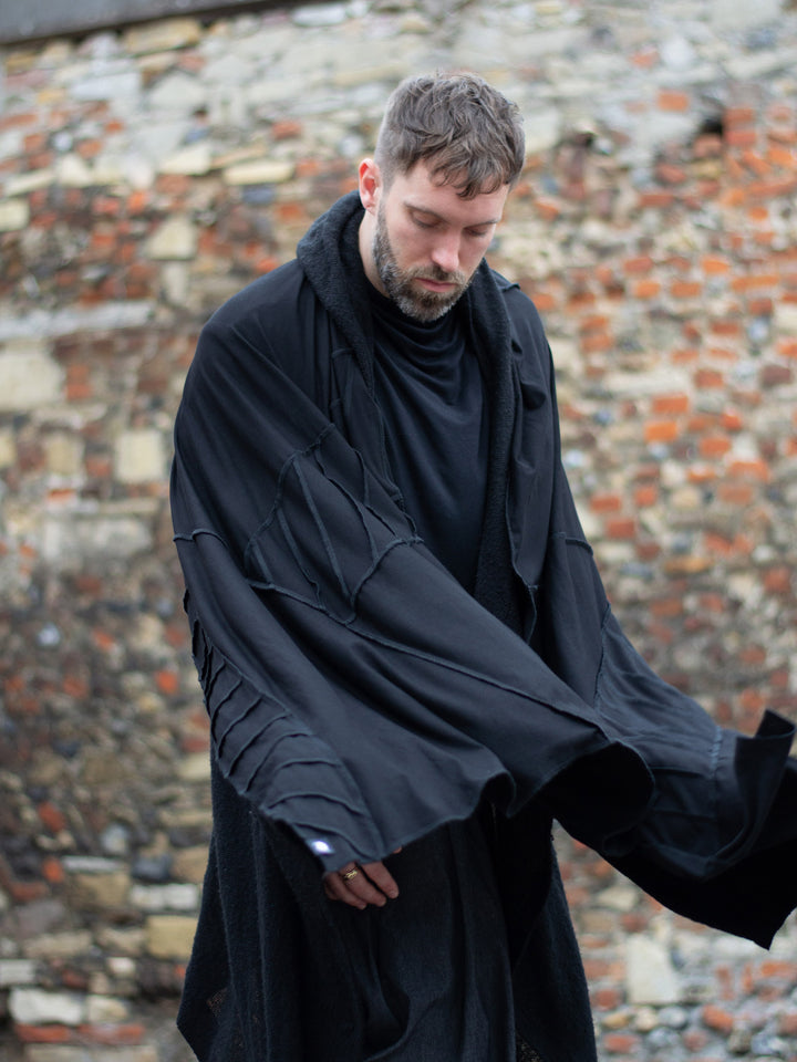 Oversized black bamboo scarf with overlock stitching, styled as a draped wrap. Futuristic and flowy, with a post-apocalyptic edge. Breathable, lightweight, and versatile for layered looks.