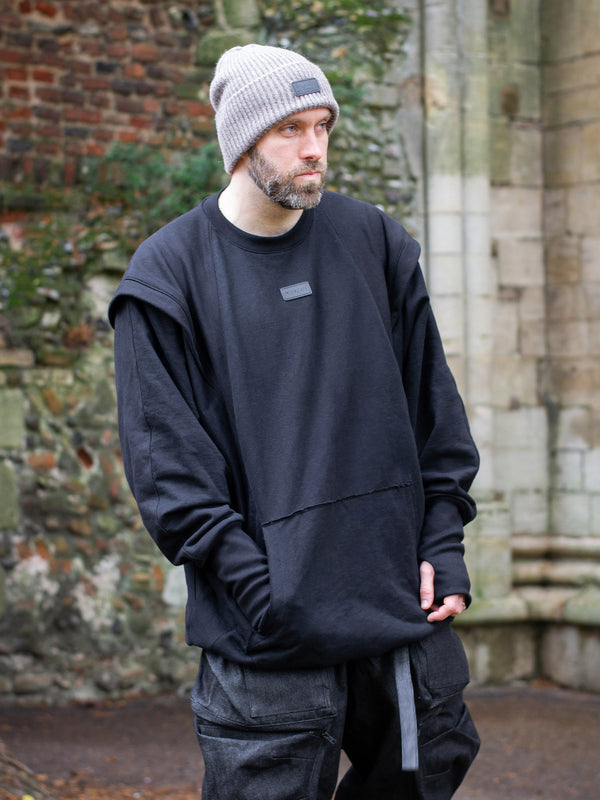Drakon oversized black batwing sweater with armour like shoulder details, thumbholes and boxy silhouette. Shown side view.