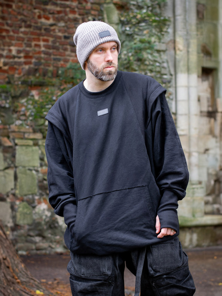 Drakon oversized black batwing sweater with armour like shoulder details, thumbholes and boxy silhouette. Shown front view.