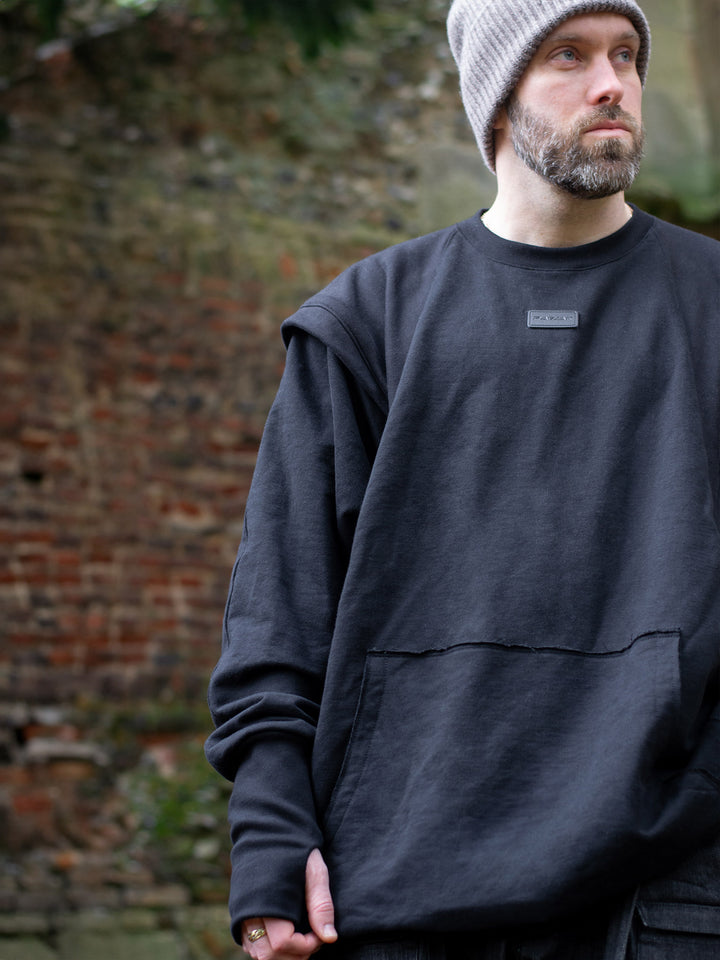 Drakon oversized black batwing sweater with armour like shoulder details, thumbholes and boxy silhouette. Shown close up.