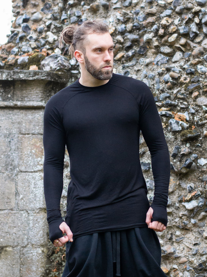 Fusion Men's Longline Tshirt with Thumbholes in Black - worn by a male model outdoors, showing a muscle fit and a relaxed pose