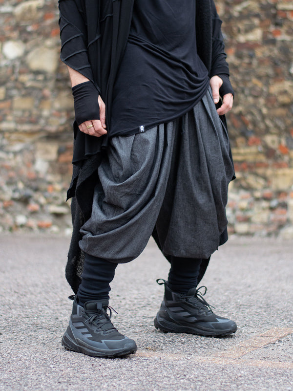 Wide-leg drop crotch ninja harem pants with voluminous pleats and tapered calf supports. Avant garde flowy mens trousers for performers, festivals or interesting looks. 