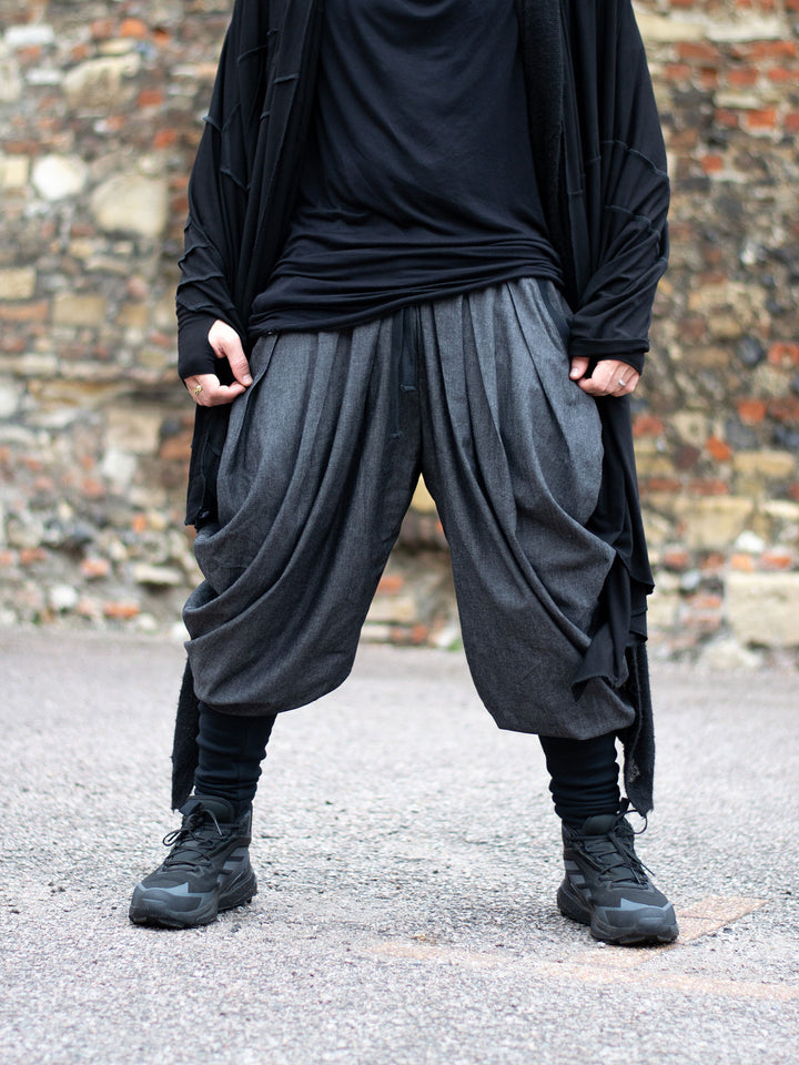 Wide-leg drop crotch ninja harem pants with voluminous pleats and tapered calf supports. Avant garde flowy mens trousers for performers, festivals or interesting looks. 
