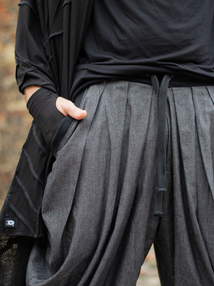 Wide-leg drop crotch ninja harem pants with voluminous pleats and tapered calf supports. Avant garde flowy mens trousers for performers, festivals or interesting looks. 