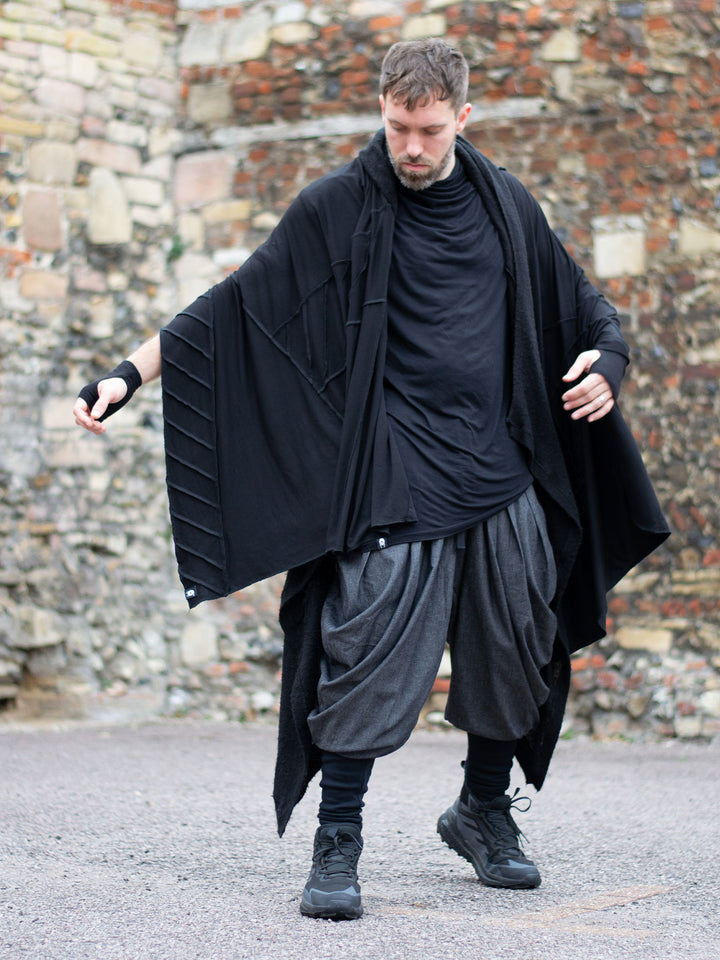 Wide-leg drop crotch ninja harem pants with voluminous pleats and tapered calf supports. Avant garde flowy mens trousers for performers, festivals or interesting looks. Combined with a draped black t-shirt and n oversized scarf with stitching details.