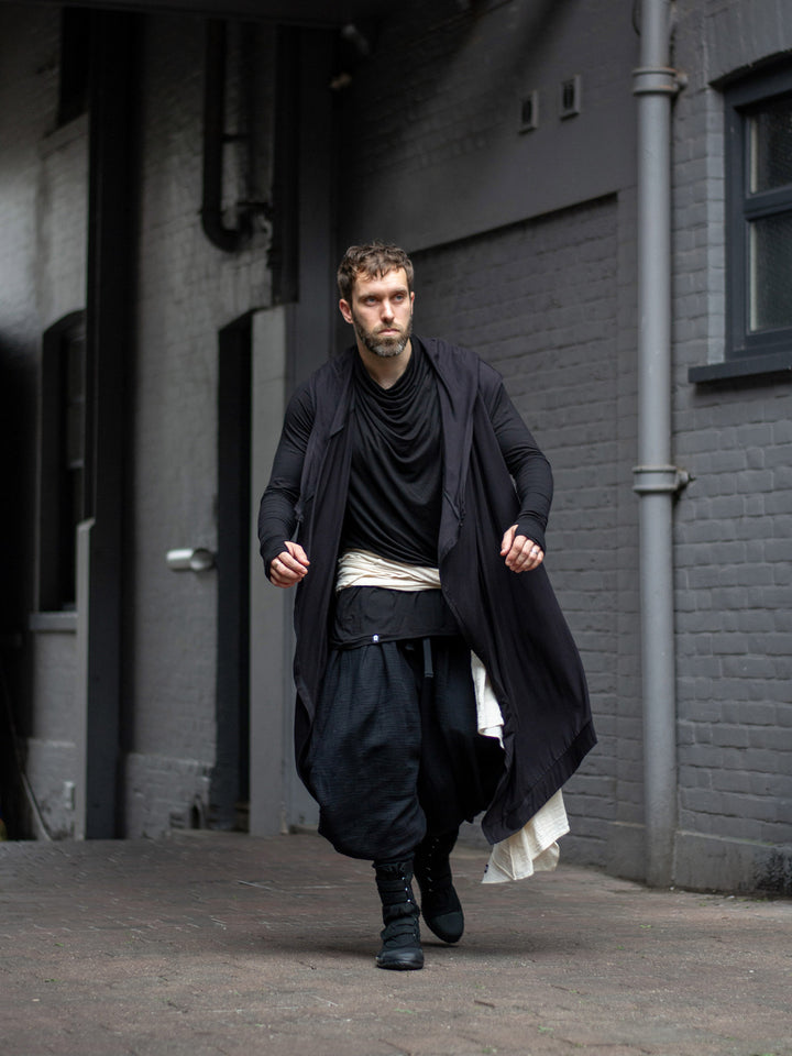 Model wearing black drop-crotch ninja pants inspired by traditional shinobi attire — Hattori harem pants in breathable muslin with pleated volume, calf supports, and a flowy, avant-garde silhouette.