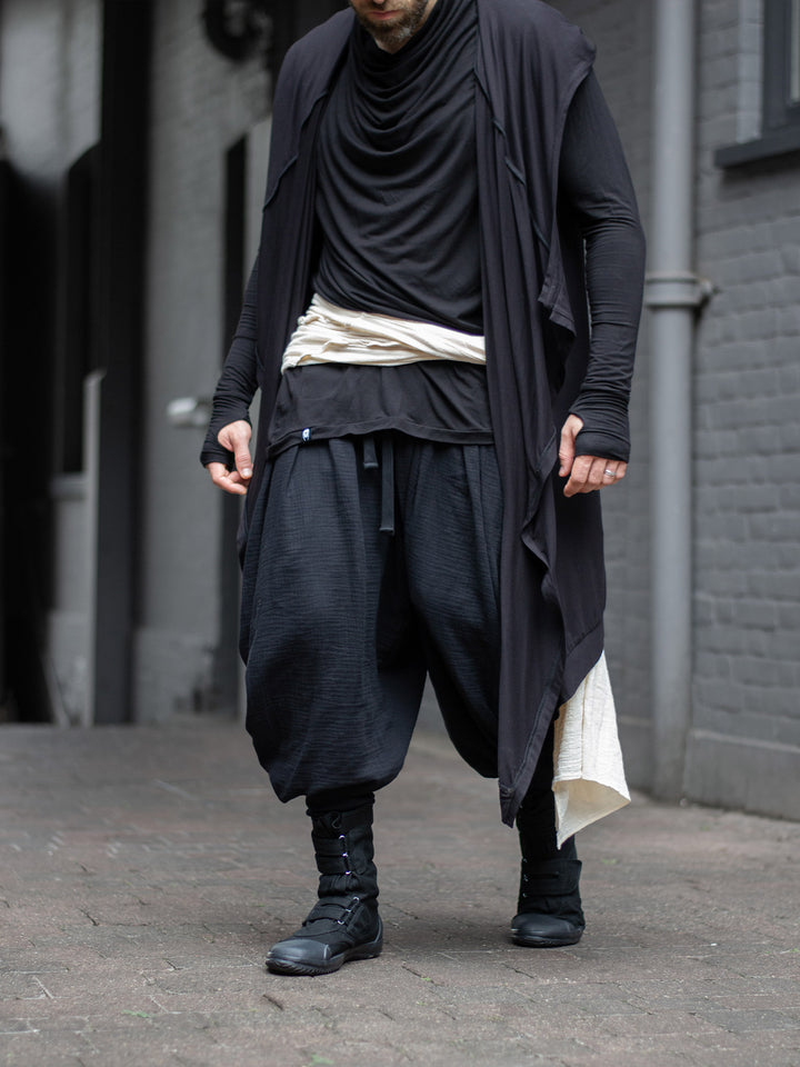 Model wearing black drop-crotch ninja pants inspired by traditional shinobi attire — Hattori harem pants in breathable muslin with pleated volume, calf supports, and a flowy, avant-garde silhouette.