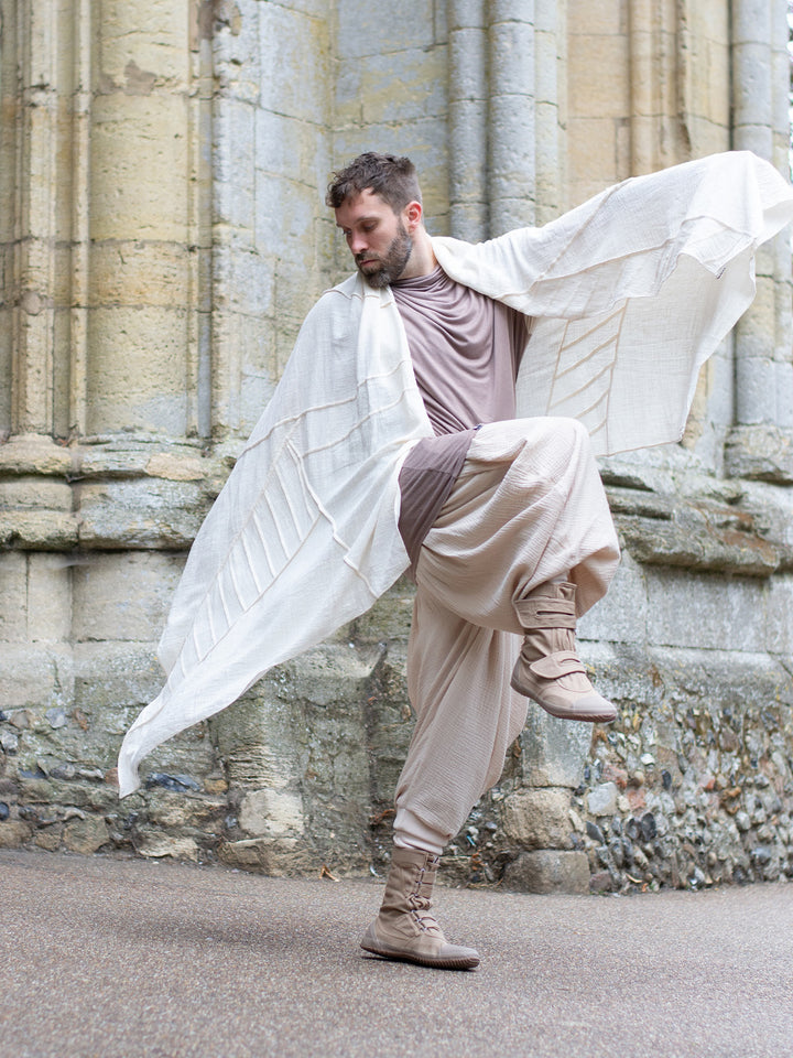 Sand drop-crotch ninja style pants made from lightweight double gauze muslin cotton, featuring wide pleated legs, ribbed calf supports, and a flowy silhouette. Inspired by traditional Japanese attire with an avant-garde, streetwear twist — ideal for summer layering, movement, and alternative festival fits.