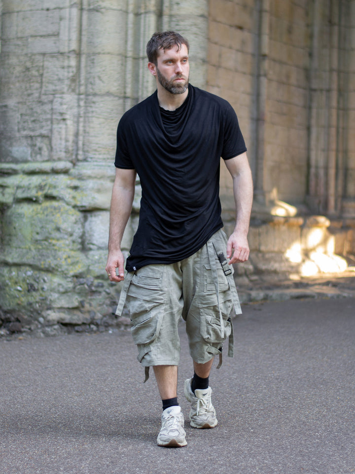 Krypt T-Shirt in black — an avant-garde, longline men’s tee made from breathable bamboo jersey. Features a draped neckline, asymmetric hem, and raglan sleeves for movement. A sculptural, apocalyptic-inspired silhouette designed for festival layering and everyday alternative styling.