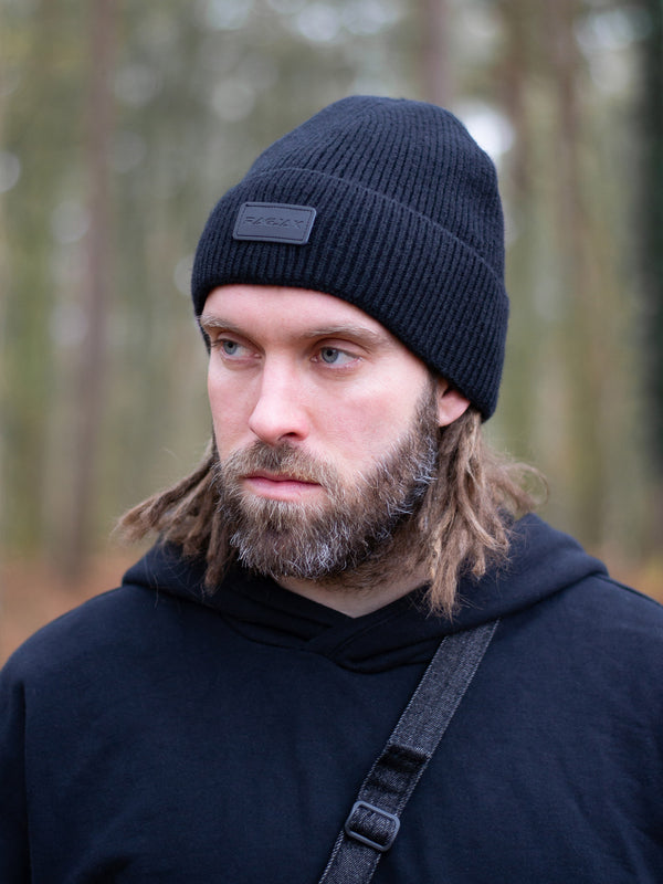 Close-up of a ribbed knit Merino wool beanie in black, featuring a turn-up cuff and a RagJak leather tag on the fold-up. A versatile and stylish winter accessory designed for warmth and durability.