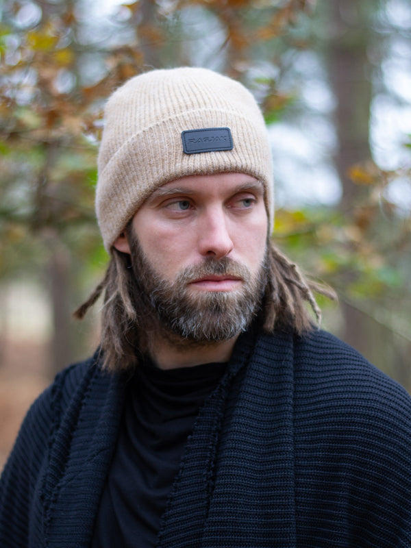 Close-up of a ribbed knit Merino wool beanie in tan beige, featuring a turn-up cuff and a RagJak leather tag on the fold-up. A versatile and stylish winter accessory designed for warmth and durability.