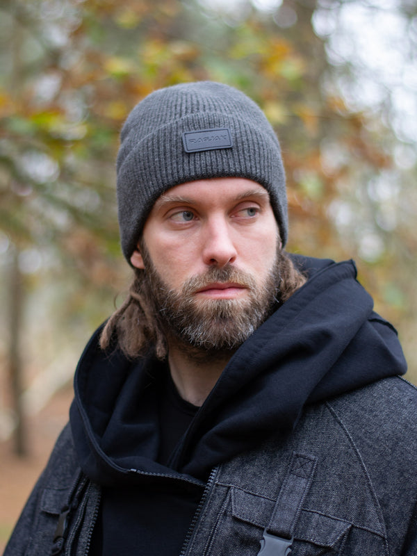 Close-up of a ribbed knit Merino wool beanie in charcoal grey, featuring a turn-up cuff and a RagJak leather tag on the fold-up. A versatile and stylish winter accessory designed for warmth and durability.