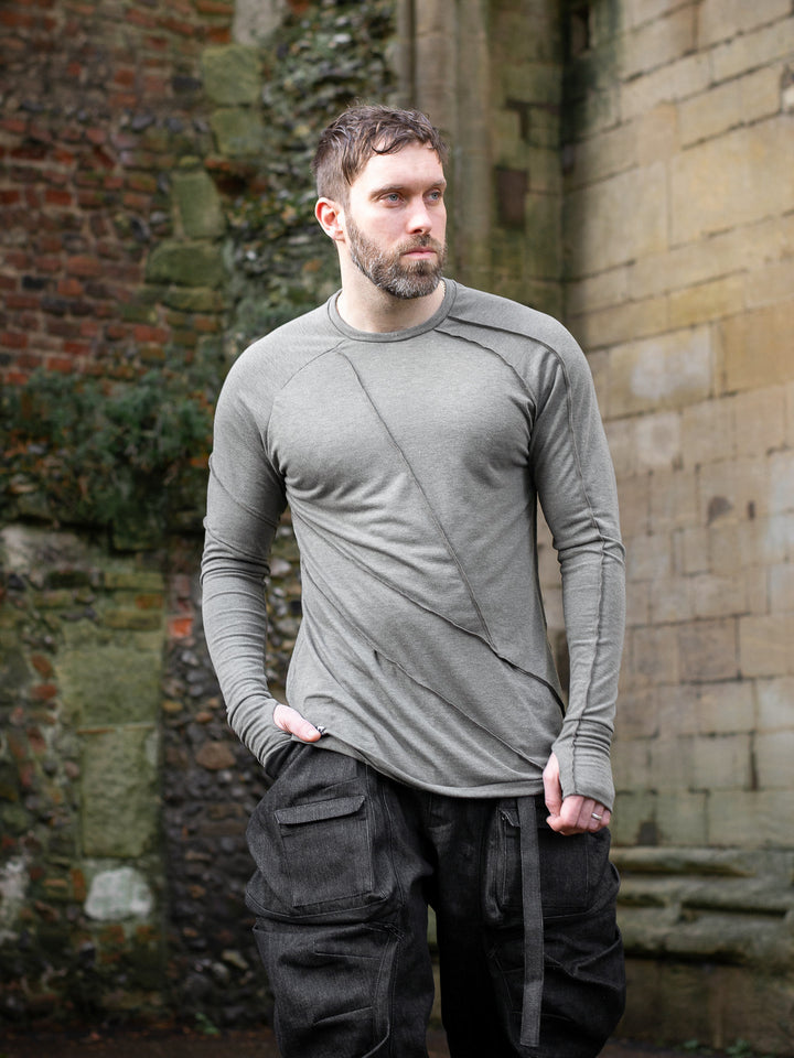 Men’s avant garde long sleeve top in Moss Grey with abstract overlock stitching, raglan sleeves, thumbholes, and longline slim silhouette. Bamboo jersey base layer - Outfit Image showing styling with denim cargos