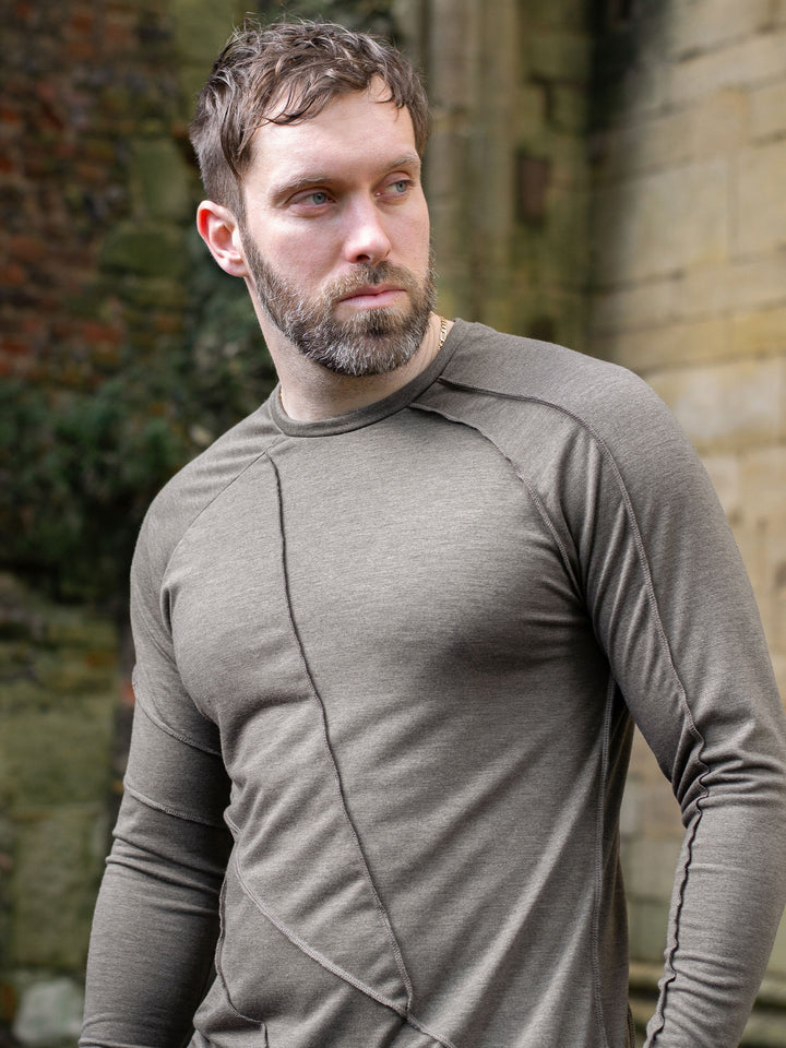 Men’s avant garde long sleeve top in Dark Taupe with abstract overlock stitching, raglan sleeves, thumbholes, and longline slim silhouette. Bamboo jersey base layer styled with techwear cargos. - Close-up of shoulder details
