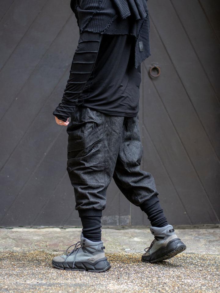 Side view of men's black denim cargo pants with relaxed drop crotch and 4 pocket design, styled with the Raider long sleeve t-shirt with thumbholes and dystopian apocalyptic stitching details.