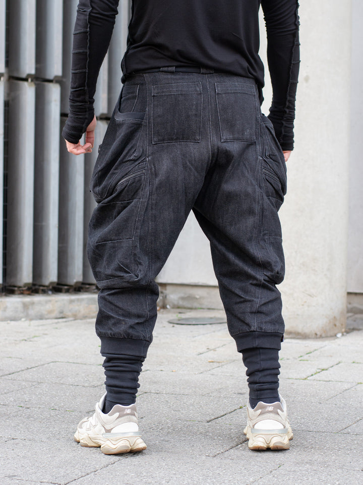 Black avant-garde cargo trousers with 10-pocket design, drop crotch fit, 15oz denim construction, metal hardware, and tactical detailing for alternative streetwear
