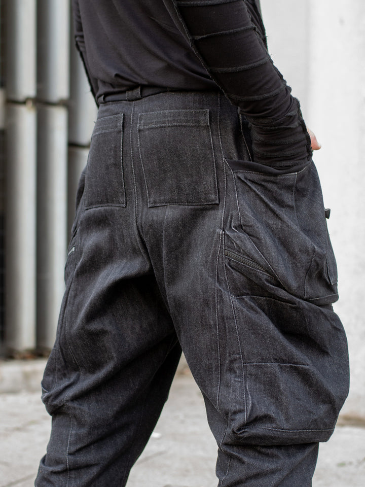 Black avant-garde cargo trousers with 10-pocket design, drop crotch fit, 15oz denim construction, metal hardware, and tactical detailing for alternative streetwear