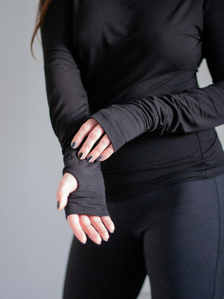 Xina Women's Roll Neck T-shirt with Thumboles in Black. A slimline silhouette with long sleeves and functional thumbholes for both casual and active styles. Close up of the thumbhole design