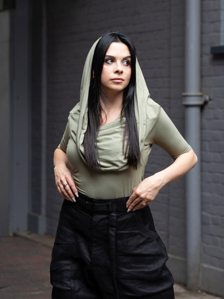 Model wearing Yara sage green short sleeve hooded t-shirt in bamboo jersey, with soft drape, double-layer hood, and fitted silhouette — alternative designer streetwear by Rags by Jak.