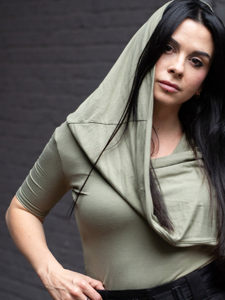 Model wearing Yara sage green short sleeve hooded t-shirt in bamboo jersey, with soft drape, double-layer hood, and fitted silhouette — alternative designer streetwear by Rags by Jak.