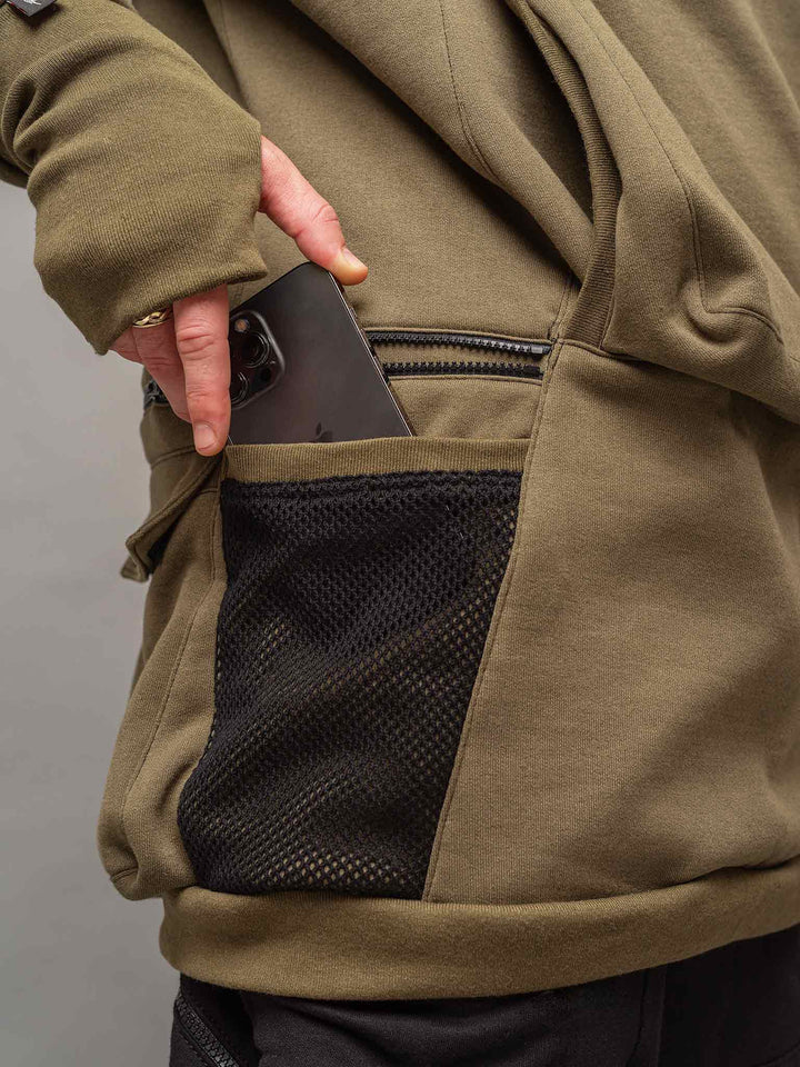Focus shot of the side mesh pocket of the Colossus Hoodie in Olive Green.