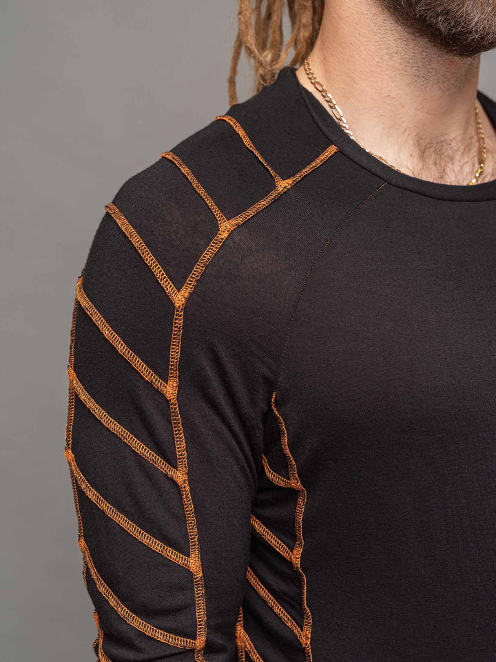 Raider dystopian avant garde men's longline tshirt in black with thumbholes and overlock contrast stitch in orange - focus on shoulder details