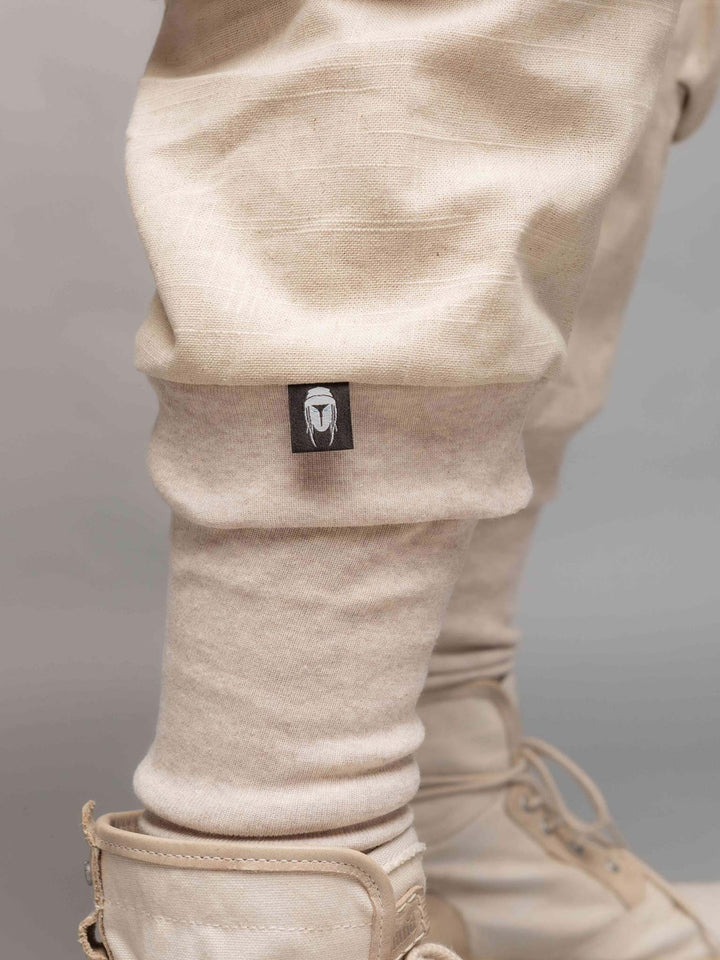 Desert Warlocks, Heavyweight linen cargo pants with 10 pockets by Rags by Jak in sand - Lower calf label view