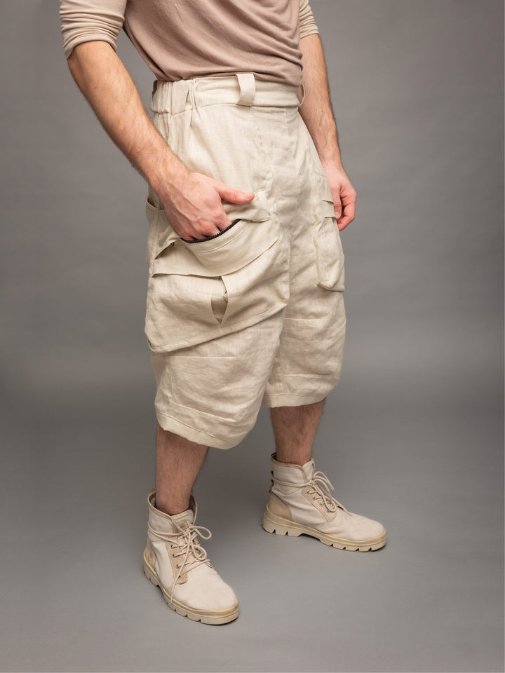 Zyrex drop crotch knee length shorts in sand with 8 pocket design - Front side view with hand in pocket